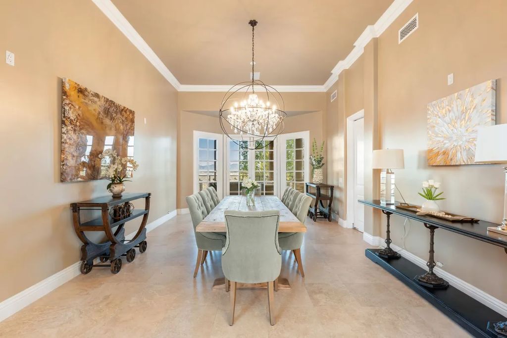 This exquisite estate offers breathtaking 360-degree views of the ocean sunsets, city lights, and Santa Monica mountains skyline, visible from its three stunning balconies. With over 9,300 square feet of space, this luxurious property boasts five bedrooms, seven bathrooms, three living rooms, formal and informal dining areas, and five beautiful fireplaces. The grand entrance through double doors leads to a dramatic 2-story foyer with 30-foot windows that flood the space with natural light, and limestone floors create an elegant touch.