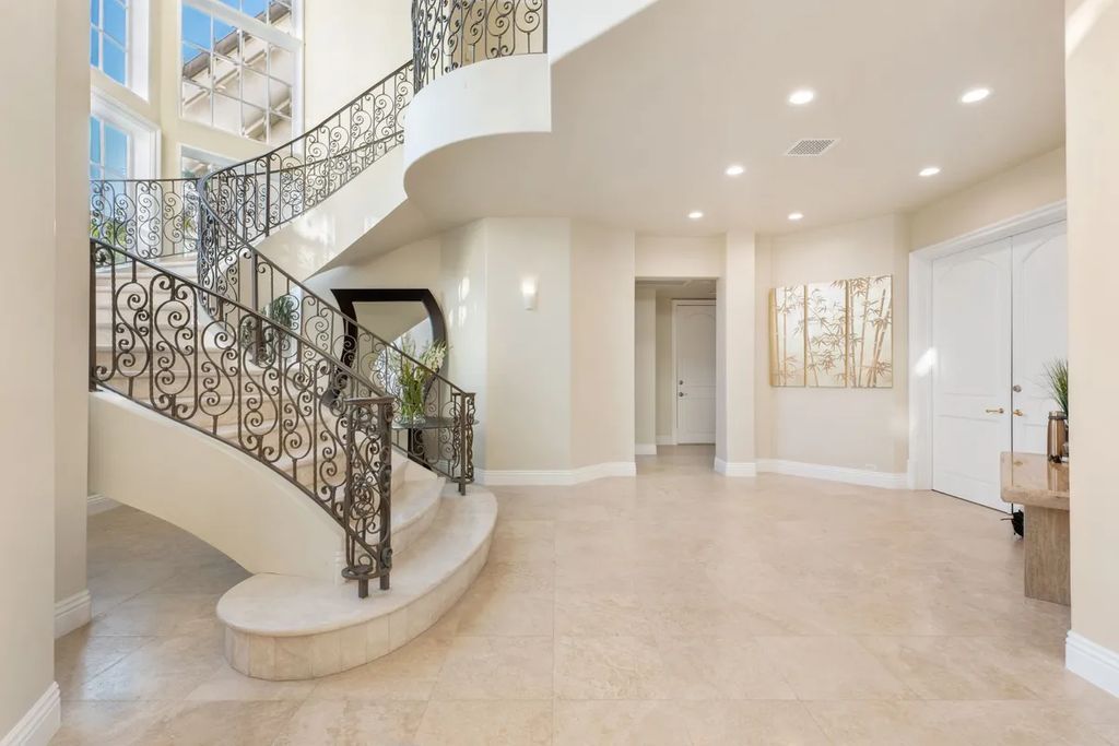 This exquisite estate offers breathtaking 360-degree views of the ocean sunsets, city lights, and Santa Monica mountains skyline, visible from its three stunning balconies. With over 9,300 square feet of space, this luxurious property boasts five bedrooms, seven bathrooms, three living rooms, formal and informal dining areas, and five beautiful fireplaces. The grand entrance through double doors leads to a dramatic 2-story foyer with 30-foot windows that flood the space with natural light, and limestone floors create an elegant touch.