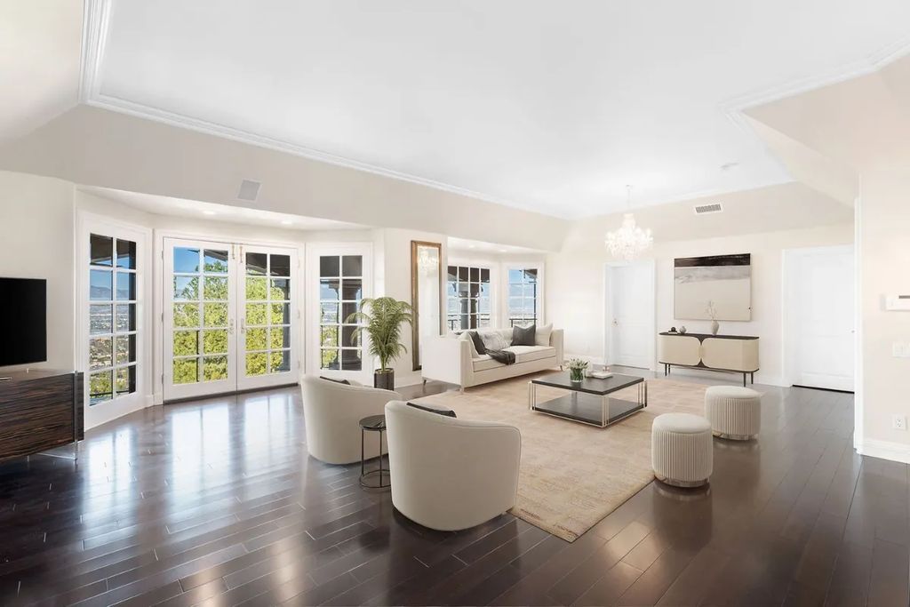 This exquisite estate offers breathtaking 360-degree views of the ocean sunsets, city lights, and Santa Monica mountains skyline, visible from its three stunning balconies. With over 9,300 square feet of space, this luxurious property boasts five bedrooms, seven bathrooms, three living rooms, formal and informal dining areas, and five beautiful fireplaces. The grand entrance through double doors leads to a dramatic 2-story foyer with 30-foot windows that flood the space with natural light, and limestone floors create an elegant touch.