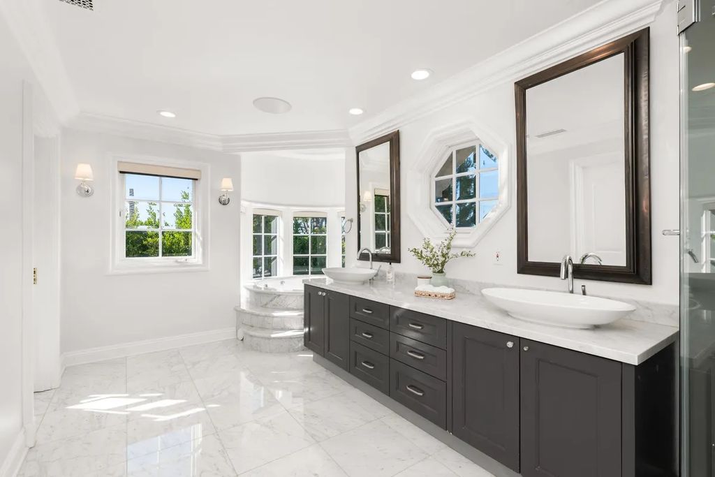 This exquisite estate offers breathtaking 360-degree views of the ocean sunsets, city lights, and Santa Monica mountains skyline, visible from its three stunning balconies. With over 9,300 square feet of space, this luxurious property boasts five bedrooms, seven bathrooms, three living rooms, formal and informal dining areas, and five beautiful fireplaces. The grand entrance through double doors leads to a dramatic 2-story foyer with 30-foot windows that flood the space with natural light, and limestone floors create an elegant touch.
