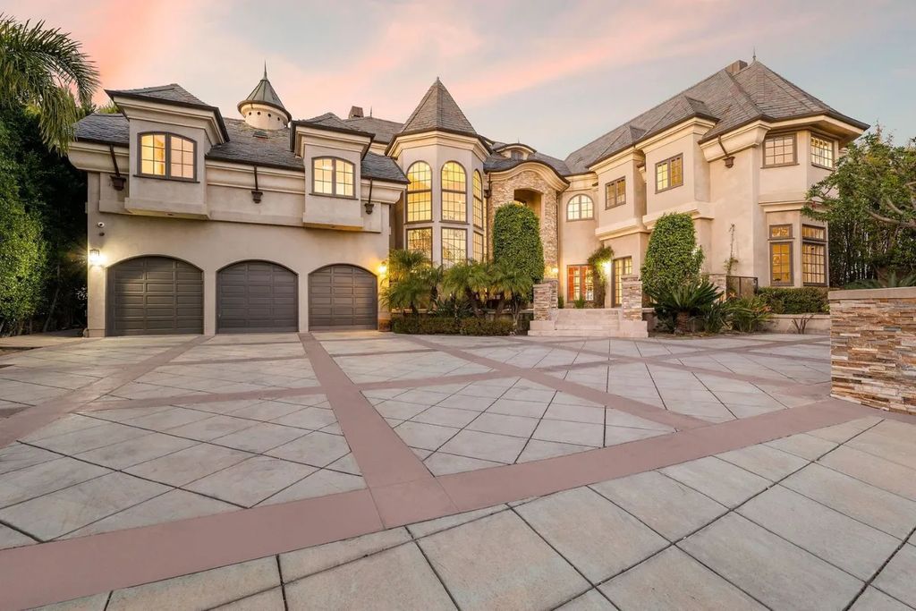 This exquisite estate offers breathtaking 360-degree views of the ocean sunsets, city lights, and Santa Monica mountains skyline, visible from its three stunning balconies. With over 9,300 square feet of space, this luxurious property boasts five bedrooms, seven bathrooms, three living rooms, formal and informal dining areas, and five beautiful fireplaces. The grand entrance through double doors leads to a dramatic 2-story foyer with 30-foot windows that flood the space with natural light, and limestone floors create an elegant touch.