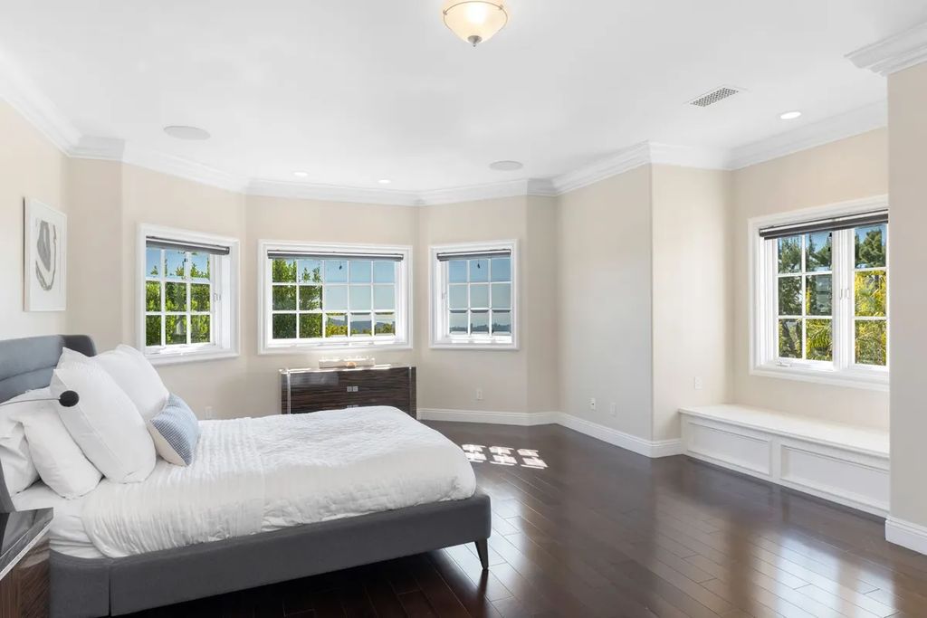 This exquisite estate offers breathtaking 360-degree views of the ocean sunsets, city lights, and Santa Monica mountains skyline, visible from its three stunning balconies. With over 9,300 square feet of space, this luxurious property boasts five bedrooms, seven bathrooms, three living rooms, formal and informal dining areas, and five beautiful fireplaces. The grand entrance through double doors leads to a dramatic 2-story foyer with 30-foot windows that flood the space with natural light, and limestone floors create an elegant touch.