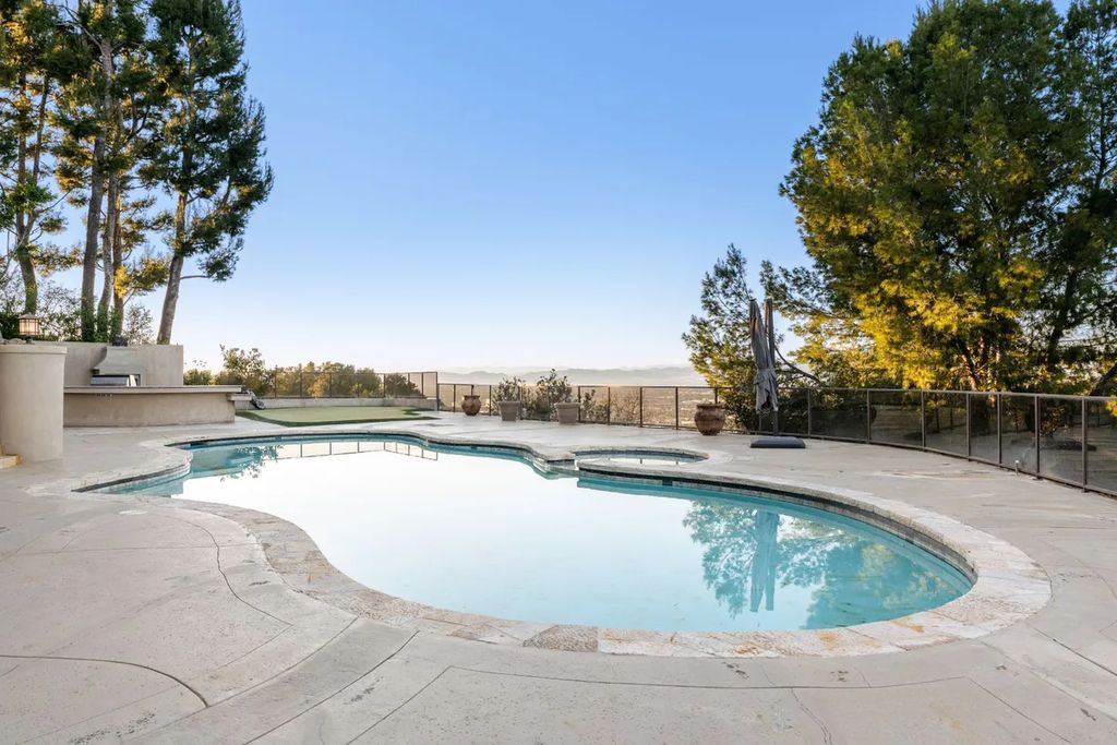This exquisite estate offers breathtaking 360-degree views of the ocean sunsets, city lights, and Santa Monica mountains skyline, visible from its three stunning balconies. With over 9,300 square feet of space, this luxurious property boasts five bedrooms, seven bathrooms, three living rooms, formal and informal dining areas, and five beautiful fireplaces. The grand entrance through double doors leads to a dramatic 2-story foyer with 30-foot windows that flood the space with natural light, and limestone floors create an elegant touch.