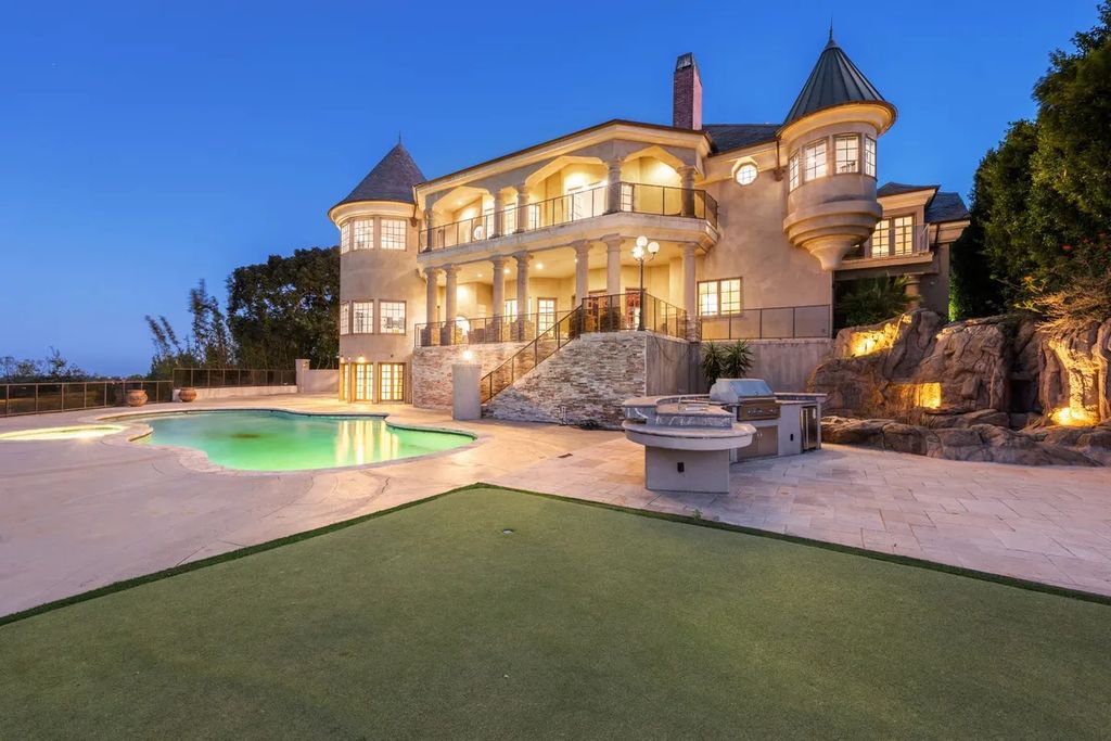 This exquisite estate offers breathtaking 360-degree views of the ocean sunsets, city lights, and Santa Monica mountains skyline, visible from its three stunning balconies. With over 9,300 square feet of space, this luxurious property boasts five bedrooms, seven bathrooms, three living rooms, formal and informal dining areas, and five beautiful fireplaces. The grand entrance through double doors leads to a dramatic 2-story foyer with 30-foot windows that flood the space with natural light, and limestone floors create an elegant touch.