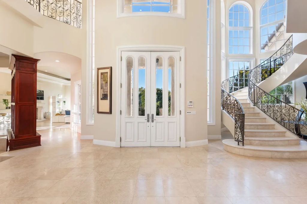 This exquisite estate offers breathtaking 360-degree views of the ocean sunsets, city lights, and Santa Monica mountains skyline, visible from its three stunning balconies. With over 9,300 square feet of space, this luxurious property boasts five bedrooms, seven bathrooms, three living rooms, formal and informal dining areas, and five beautiful fireplaces. The grand entrance through double doors leads to a dramatic 2-story foyer with 30-foot windows that flood the space with natural light, and limestone floors create an elegant touch.