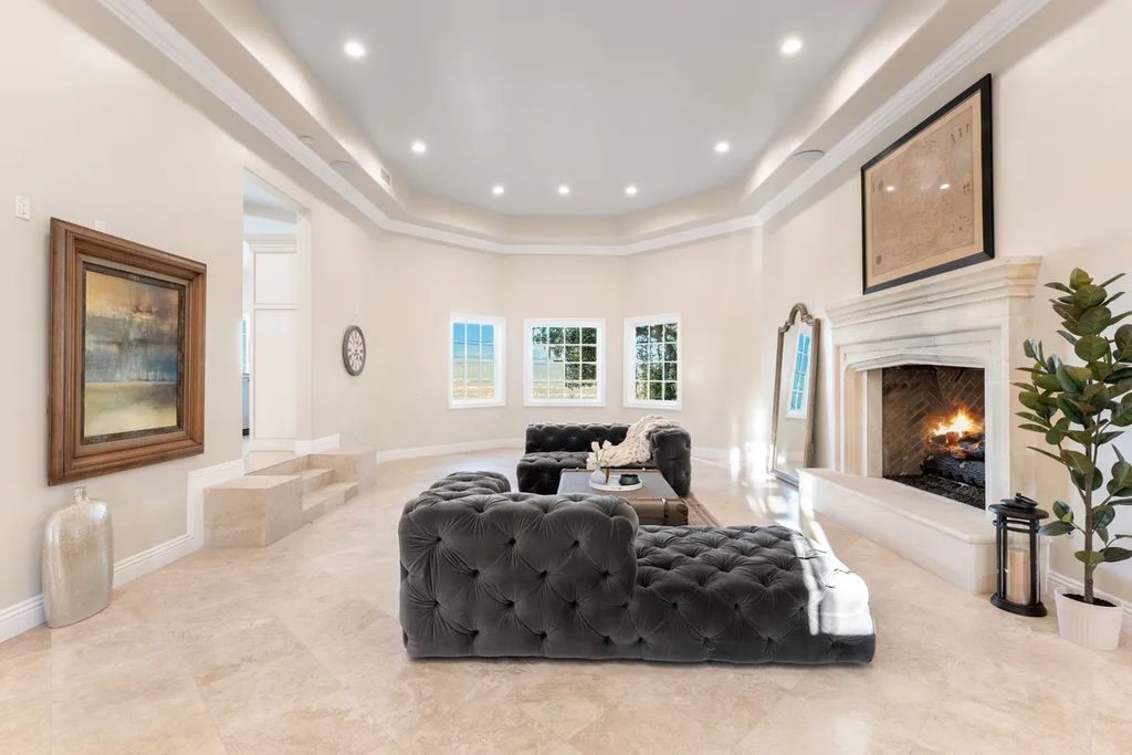 This exquisite estate offers breathtaking 360-degree views of the ocean sunsets, city lights, and Santa Monica mountains skyline, visible from its three stunning balconies. With over 9,300 square feet of space, this luxurious property boasts five bedrooms, seven bathrooms, three living rooms, formal and informal dining areas, and five beautiful fireplaces. The grand entrance through double doors leads to a dramatic 2-story foyer with 30-foot windows that flood the space with natural light, and limestone floors create an elegant touch.