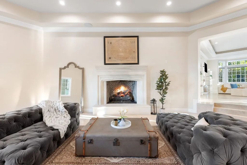 This exquisite estate offers breathtaking 360-degree views of the ocean sunsets, city lights, and Santa Monica mountains skyline, visible from its three stunning balconies. With over 9,300 square feet of space, this luxurious property boasts five bedrooms, seven bathrooms, three living rooms, formal and informal dining areas, and five beautiful fireplaces. The grand entrance through double doors leads to a dramatic 2-story foyer with 30-foot windows that flood the space with natural light, and limestone floors create an elegant touch.
