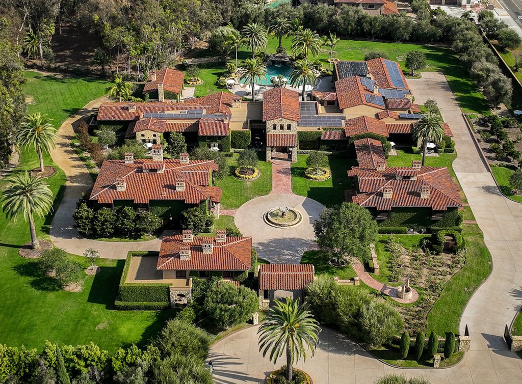 Indulge in the lavishness of a sprawling Mediterranean estate located on 4.71 acres in the sought-after Rancho Santa Fe. This private gated property boasts a grand Tuscan villa with a circular drive featuring a serene fountain and four separate stone and vine-covered structures surrounded by lush greenery.