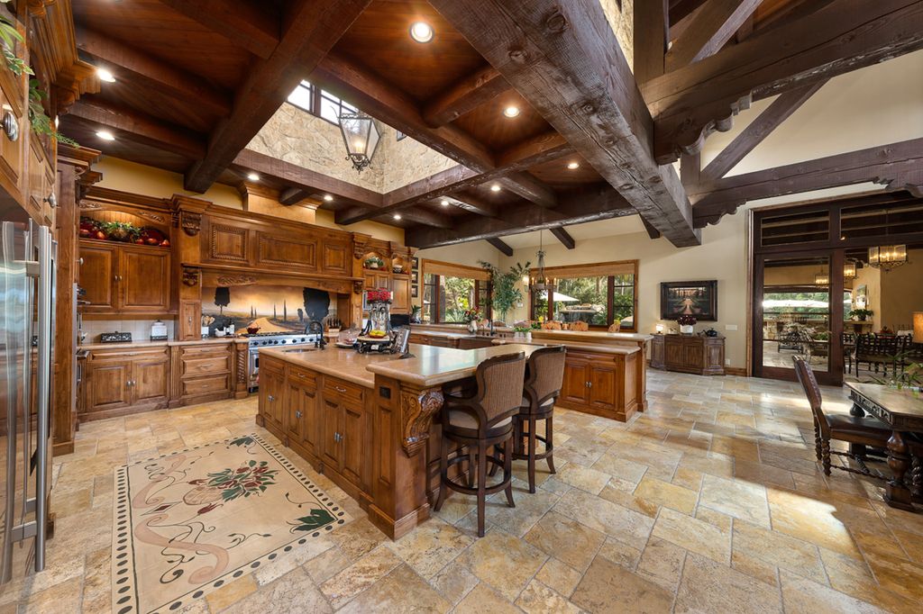 Indulge in the lavishness of a sprawling Mediterranean estate located on 4.71 acres in the sought-after Rancho Santa Fe. This private gated property boasts a grand Tuscan villa with a circular drive featuring a serene fountain and four separate stone and vine-covered structures surrounded by lush greenery.