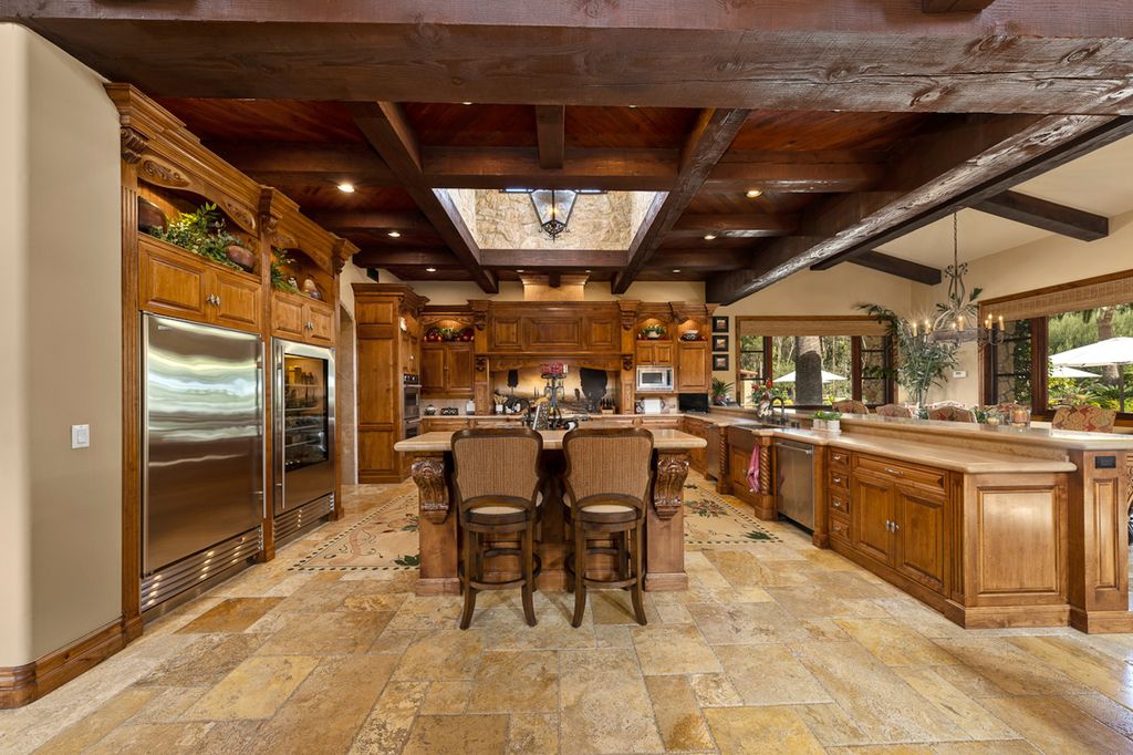 Indulge in the lavishness of a sprawling Mediterranean estate located on 4.71 acres in the sought-after Rancho Santa Fe. This private gated property boasts a grand Tuscan villa with a circular drive featuring a serene fountain and four separate stone and vine-covered structures surrounded by lush greenery.