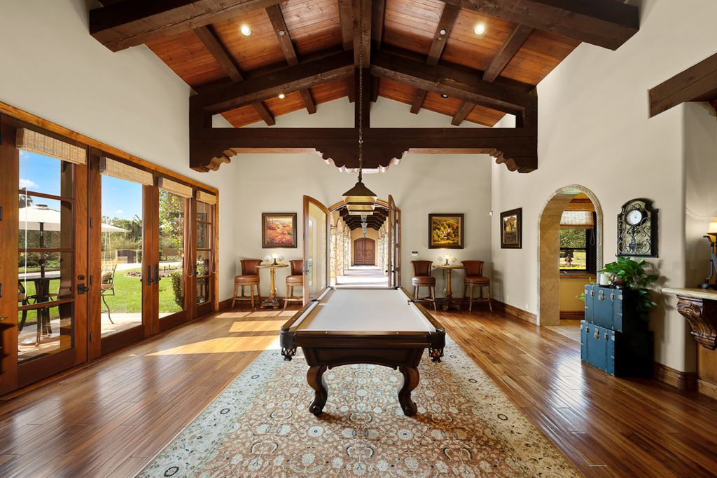 Indulge in the lavishness of a sprawling Mediterranean estate located on 4.71 acres in the sought-after Rancho Santa Fe. This private gated property boasts a grand Tuscan villa with a circular drive featuring a serene fountain and four separate stone and vine-covered structures surrounded by lush greenery.