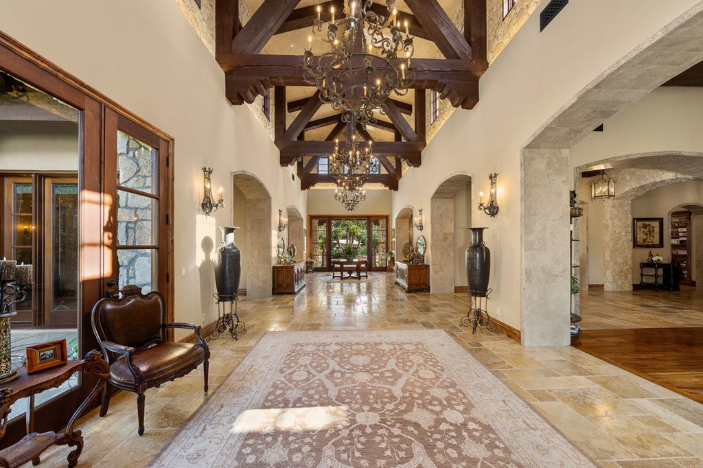 Indulge in the lavishness of a sprawling Mediterranean estate located on 4.71 acres in the sought-after Rancho Santa Fe. This private gated property boasts a grand Tuscan villa with a circular drive featuring a serene fountain and four separate stone and vine-covered structures surrounded by lush greenery.