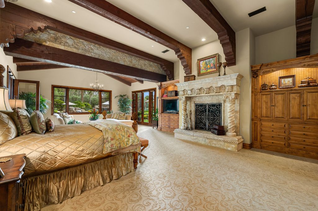 Indulge in the lavishness of a sprawling Mediterranean estate located on 4.71 acres in the sought-after Rancho Santa Fe. This private gated property boasts a grand Tuscan villa with a circular drive featuring a serene fountain and four separate stone and vine-covered structures surrounded by lush greenery.