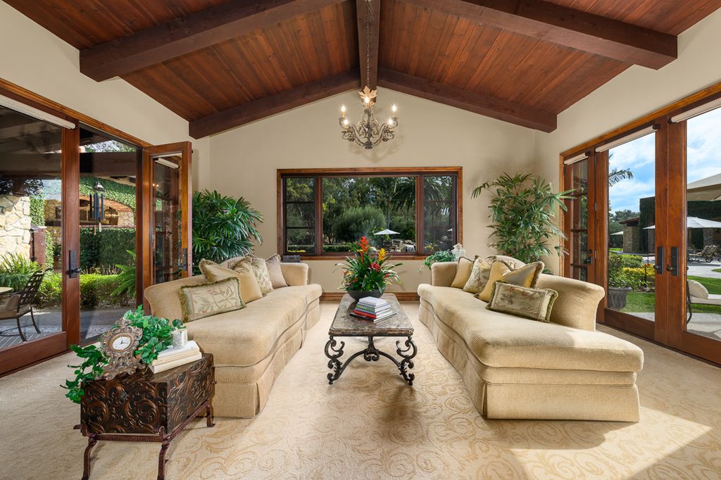 Indulge in the lavishness of a sprawling Mediterranean estate located on 4.71 acres in the sought-after Rancho Santa Fe. This private gated property boasts a grand Tuscan villa with a circular drive featuring a serene fountain and four separate stone and vine-covered structures surrounded by lush greenery.