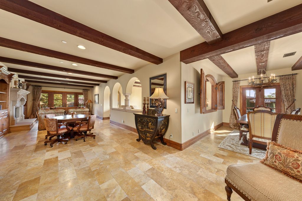 Indulge in the lavishness of a sprawling Mediterranean estate located on 4.71 acres in the sought-after Rancho Santa Fe. This private gated property boasts a grand Tuscan villa with a circular drive featuring a serene fountain and four separate stone and vine-covered structures surrounded by lush greenery.