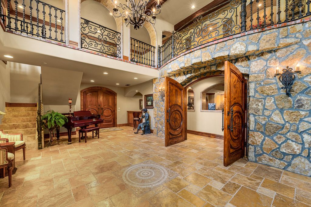 Indulge in the lavishness of a sprawling Mediterranean estate located on 4.71 acres in the sought-after Rancho Santa Fe. This private gated property boasts a grand Tuscan villa with a circular drive featuring a serene fountain and four separate stone and vine-covered structures surrounded by lush greenery.