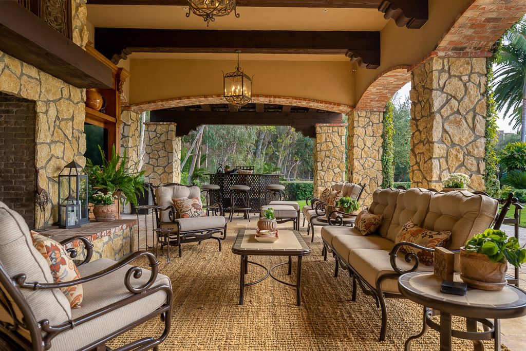 Indulge in the lavishness of a sprawling Mediterranean estate located on 4.71 acres in the sought-after Rancho Santa Fe. This private gated property boasts a grand Tuscan villa with a circular drive featuring a serene fountain and four separate stone and vine-covered structures surrounded by lush greenery.
