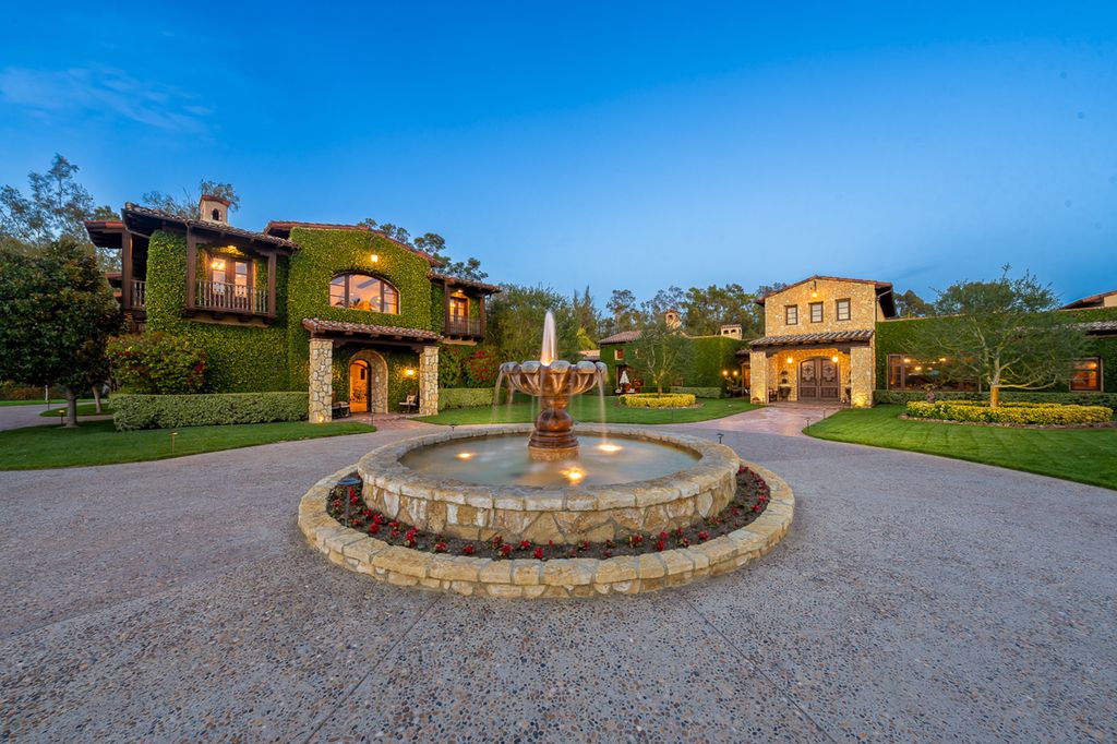 Indulge in the lavishness of a sprawling Mediterranean estate located on 4.71 acres in the sought-after Rancho Santa Fe. This private gated property boasts a grand Tuscan villa with a circular drive featuring a serene fountain and four separate stone and vine-covered structures surrounded by lush greenery.