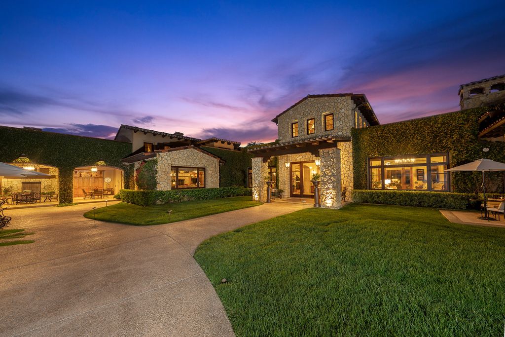 Indulge in the lavishness of a sprawling Mediterranean estate located on 4.71 acres in the sought-after Rancho Santa Fe. This private gated property boasts a grand Tuscan villa with a circular drive featuring a serene fountain and four separate stone and vine-covered structures surrounded by lush greenery.