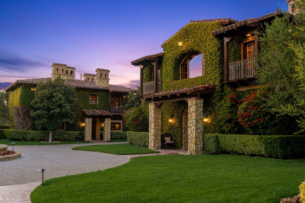 Indulge in the lavishness of a sprawling Mediterranean estate located on 4.71 acres in the sought-after Rancho Santa Fe. This private gated property boasts a grand Tuscan villa with a circular drive featuring a serene fountain and four separate stone and vine-covered structures surrounded by lush greenery.