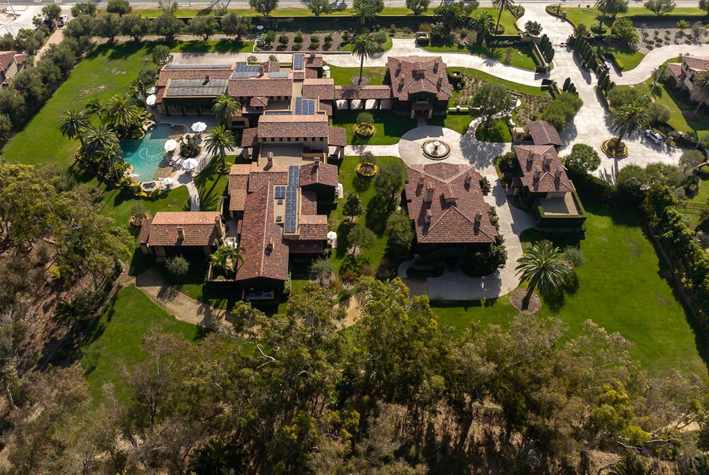 Indulge in the lavishness of a sprawling Mediterranean estate located on 4.71 acres in the sought-after Rancho Santa Fe. This private gated property boasts a grand Tuscan villa with a circular drive featuring a serene fountain and four separate stone and vine-covered structures surrounded by lush greenery.
