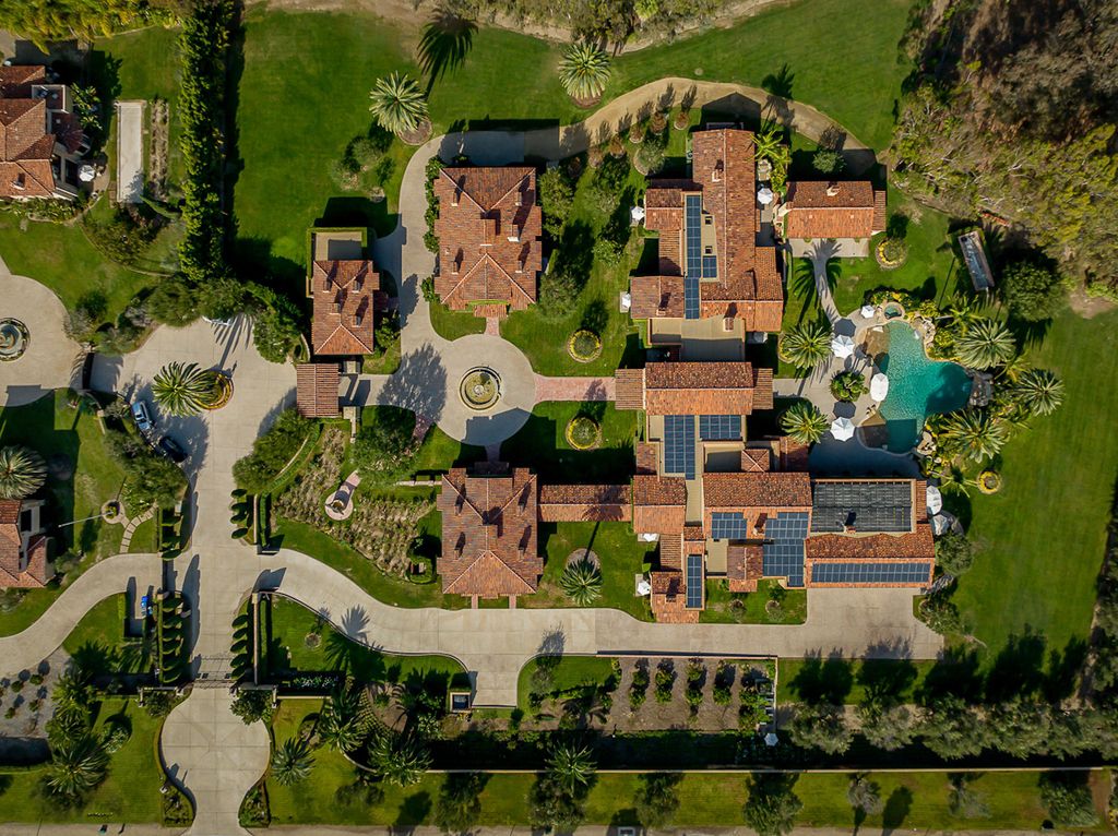 Indulge in the lavishness of a sprawling Mediterranean estate located on 4.71 acres in the sought-after Rancho Santa Fe. This private gated property boasts a grand Tuscan villa with a circular drive featuring a serene fountain and four separate stone and vine-covered structures surrounded by lush greenery.