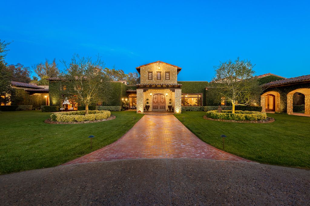 Indulge in the lavishness of a sprawling Mediterranean estate located on 4.71 acres in the sought-after Rancho Santa Fe. This private gated property boasts a grand Tuscan villa with a circular drive featuring a serene fountain and four separate stone and vine-covered structures surrounded by lush greenery.
