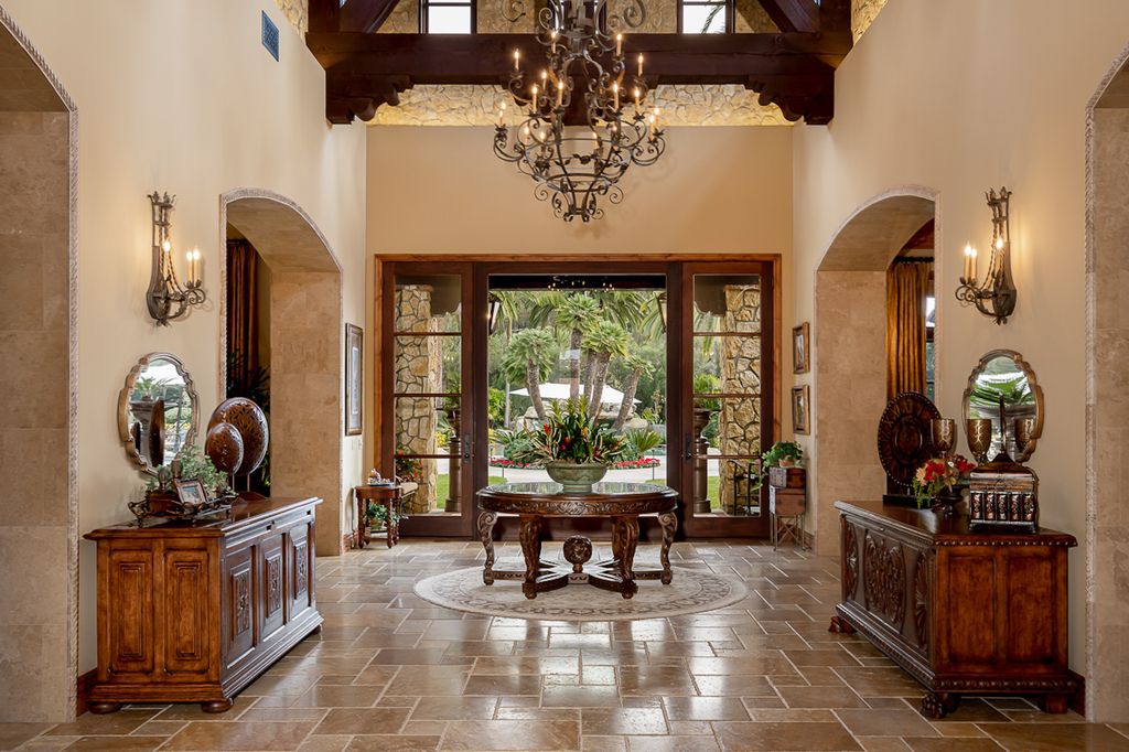 Indulge in the lavishness of a sprawling Mediterranean estate located on 4.71 acres in the sought-after Rancho Santa Fe. This private gated property boasts a grand Tuscan villa with a circular drive featuring a serene fountain and four separate stone and vine-covered structures surrounded by lush greenery.