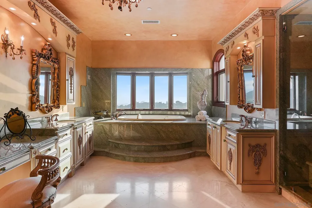 Elevated on a hill in Blossom Valley, this exquisite home offers a living experience that is truly unmatched. Nestled within a gated estate, the property expands across six acres of meticulously landscaped grounds, showcasing natural rock formations and a vibrant variety of palm trees, succulents, and blooming flowers. Embracing eco-friendly features such as a ground-water well and solar panels, this residence seamlessly blends sustainability with luxurious living. 15987 Broad Oaks Road Home in El Cajon, California.