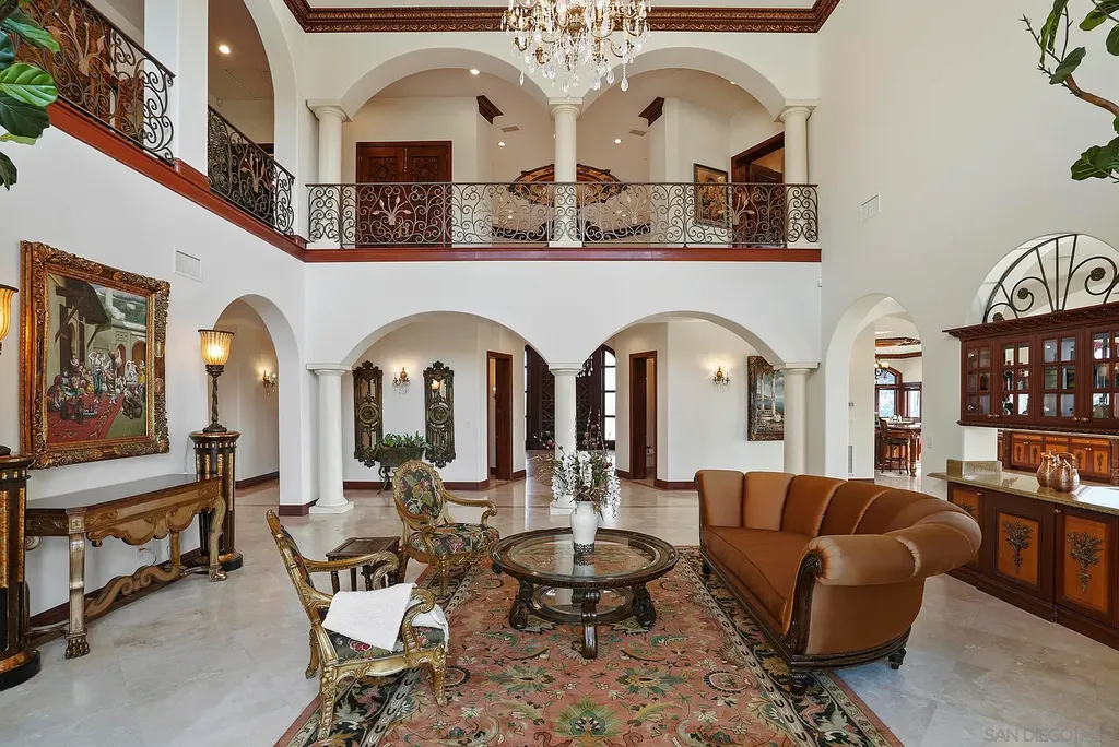 Elevated on a hill in Blossom Valley, this exquisite home offers a living experience that is truly unmatched. Nestled within a gated estate, the property expands across six acres of meticulously landscaped grounds, showcasing natural rock formations and a vibrant variety of palm trees, succulents, and blooming flowers. Embracing eco-friendly features such as a ground-water well and solar panels, this residence seamlessly blends sustainability with luxurious living. 15987 Broad Oaks Road Home in El Cajon, California.