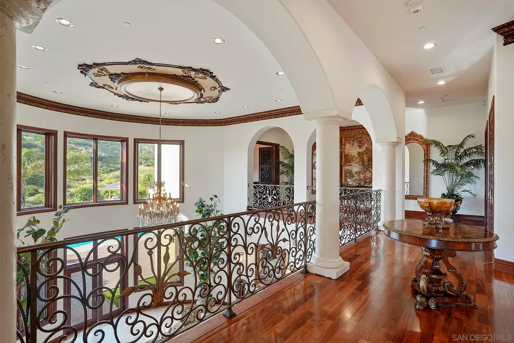 Elevated on a hill in Blossom Valley, this exquisite home offers a living experience that is truly unmatched. Nestled within a gated estate, the property expands across six acres of meticulously landscaped grounds, showcasing natural rock formations and a vibrant variety of palm trees, succulents, and blooming flowers. Embracing eco-friendly features such as a ground-water well and solar panels, this residence seamlessly blends sustainability with luxurious living. 15987 Broad Oaks Road Home in El Cajon, California.