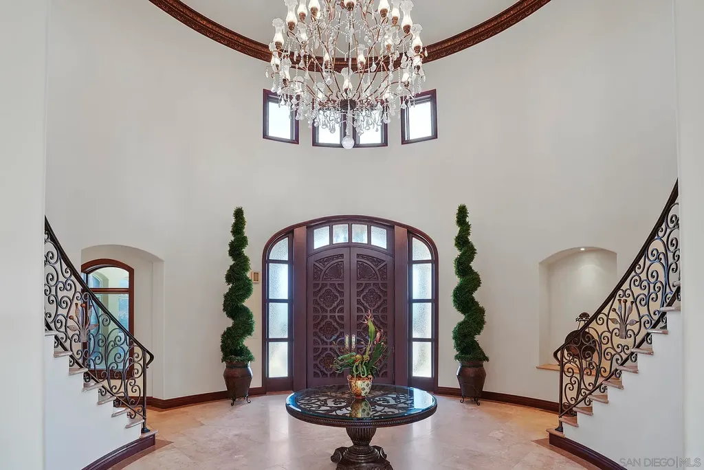 Elevated on a hill in Blossom Valley, this exquisite home offers a living experience that is truly unmatched. Nestled within a gated estate, the property expands across six acres of meticulously landscaped grounds, showcasing natural rock formations and a vibrant variety of palm trees, succulents, and blooming flowers. Embracing eco-friendly features such as a ground-water well and solar panels, this residence seamlessly blends sustainability with luxurious living. 15987 Broad Oaks Road Home in El Cajon, California.