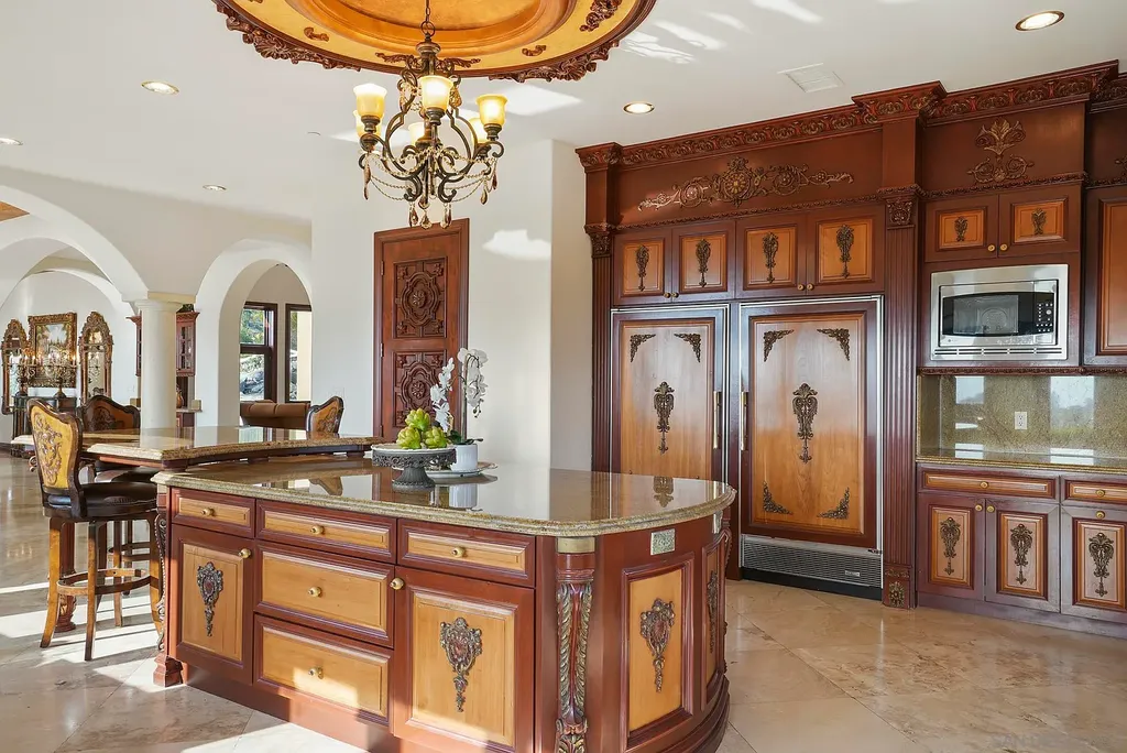 Elevated on a hill in Blossom Valley, this exquisite home offers a living experience that is truly unmatched. Nestled within a gated estate, the property expands across six acres of meticulously landscaped grounds, showcasing natural rock formations and a vibrant variety of palm trees, succulents, and blooming flowers. Embracing eco-friendly features such as a ground-water well and solar panels, this residence seamlessly blends sustainability with luxurious living. 15987 Broad Oaks Road Home in El Cajon, California.