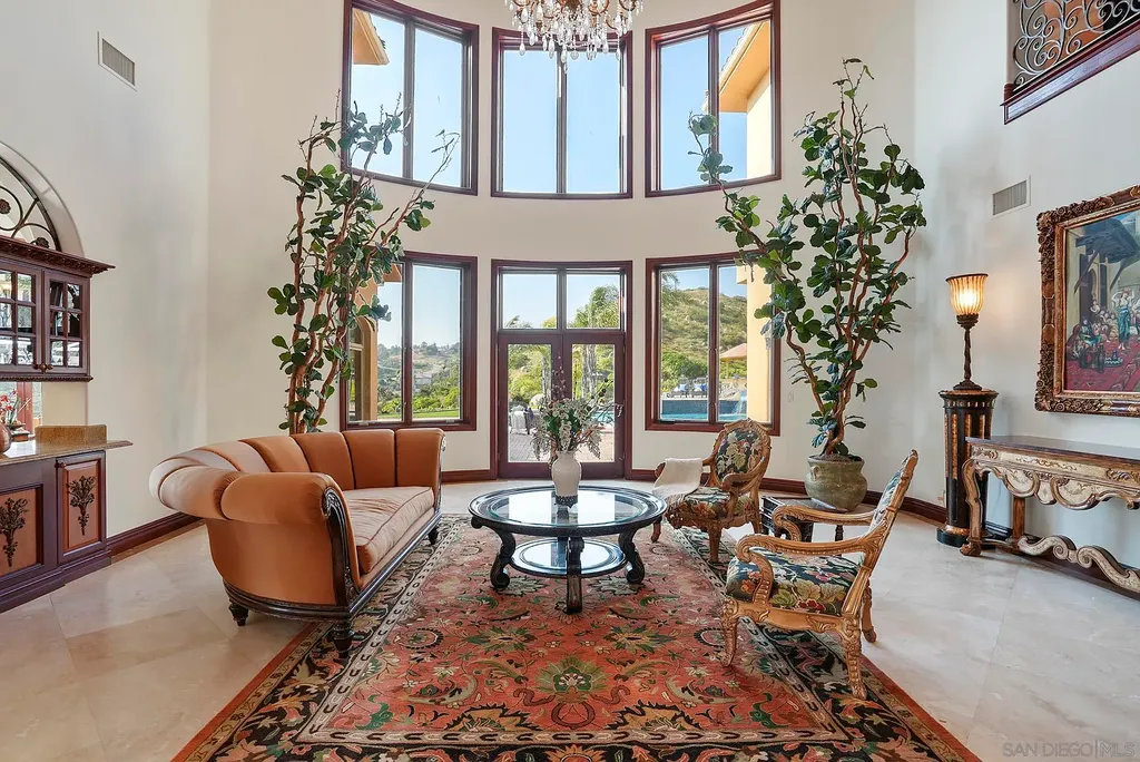 Elevated on a hill in Blossom Valley, this exquisite home offers a living experience that is truly unmatched. Nestled within a gated estate, the property expands across six acres of meticulously landscaped grounds, showcasing natural rock formations and a vibrant variety of palm trees, succulents, and blooming flowers. Embracing eco-friendly features such as a ground-water well and solar panels, this residence seamlessly blends sustainability with luxurious living. 15987 Broad Oaks Road Home in El Cajon, California.