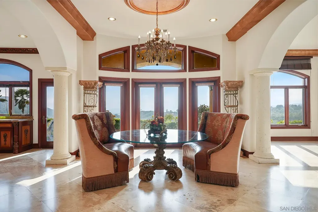 Elevated on a hill in Blossom Valley, this exquisite home offers a living experience that is truly unmatched. Nestled within a gated estate, the property expands across six acres of meticulously landscaped grounds, showcasing natural rock formations and a vibrant variety of palm trees, succulents, and blooming flowers. Embracing eco-friendly features such as a ground-water well and solar panels, this residence seamlessly blends sustainability with luxurious living. 15987 Broad Oaks Road Home in El Cajon, California.