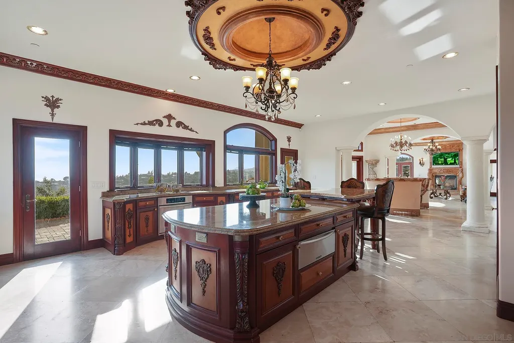 Elevated on a hill in Blossom Valley, this exquisite home offers a living experience that is truly unmatched. Nestled within a gated estate, the property expands across six acres of meticulously landscaped grounds, showcasing natural rock formations and a vibrant variety of palm trees, succulents, and blooming flowers. Embracing eco-friendly features such as a ground-water well and solar panels, this residence seamlessly blends sustainability with luxurious living. 15987 Broad Oaks Road Home in El Cajon, California.