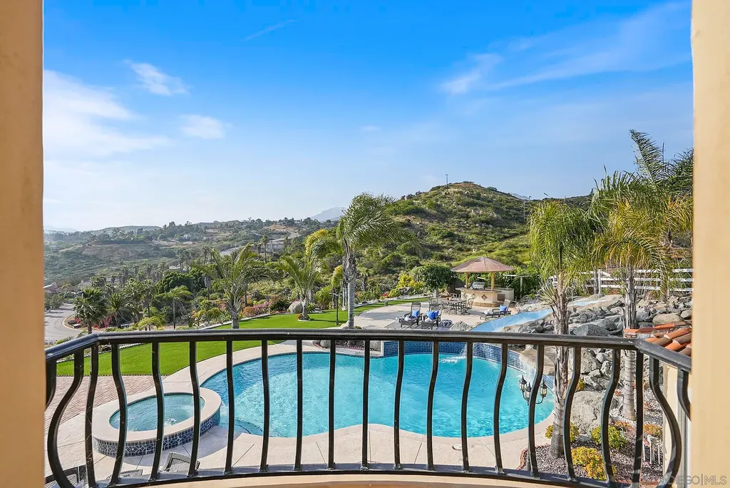 Elevated on a hill in Blossom Valley, this exquisite home offers a living experience that is truly unmatched. Nestled within a gated estate, the property expands across six acres of meticulously landscaped grounds, showcasing natural rock formations and a vibrant variety of palm trees, succulents, and blooming flowers. Embracing eco-friendly features such as a ground-water well and solar panels, this residence seamlessly blends sustainability with luxurious living. 15987 Broad Oaks Road Home in El Cajon, California.