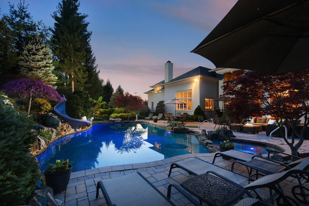16 Tall Timber Lane Home in Bernards Township, New Jersey. Discover an extraordinary French Chateau-inspired property boasting nearly 12,000 sq ft of living space. This remarkable estate offers unparalleled luxury, featuring special amenities such as an elevator for easy accessibility, a first-floor guest suite, and radiant heated floors throughout, including the basement and garage. Indulge in the opulent 4,200 sq ft walk-out lower level, featuring high ceilings, a movie theater, expansive bar, gym, full spa bathroom with sauna, workshop, second laundry room, multiple entertainment areas, and potential for a sixth bedroom ensuite.
