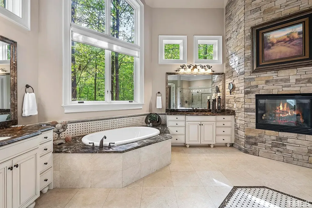 6040 Over Hadden Court Home in Raleigh, North Carolina. Indulge in the epitome of serenity and luxury at the prestigious Don Collins Estate. Nestled on 1.69 acres and embraced by the tranquil beauty of the Falls Lake wooded buffer, this remarkable residence offers an exquisite escape. Immerse yourself in timeless elegance, from the grand entrance with its stunning barreled ceiling to the imported stone accents, cathedral, coffered, and vaulted ceilings, travertine tile, and Brazilian cherry hardwood floors throughout the main level.