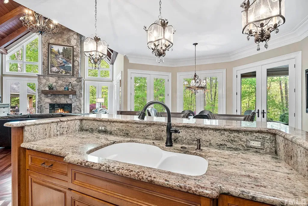 6040 Over Hadden Court Home in Raleigh, North Carolina. Indulge in the epitome of serenity and luxury at the prestigious Don Collins Estate. Nestled on 1.69 acres and embraced by the tranquil beauty of the Falls Lake wooded buffer, this remarkable residence offers an exquisite escape. Immerse yourself in timeless elegance, from the grand entrance with its stunning barreled ceiling to the imported stone accents, cathedral, coffered, and vaulted ceilings, travertine tile, and Brazilian cherry hardwood floors throughout the main level.