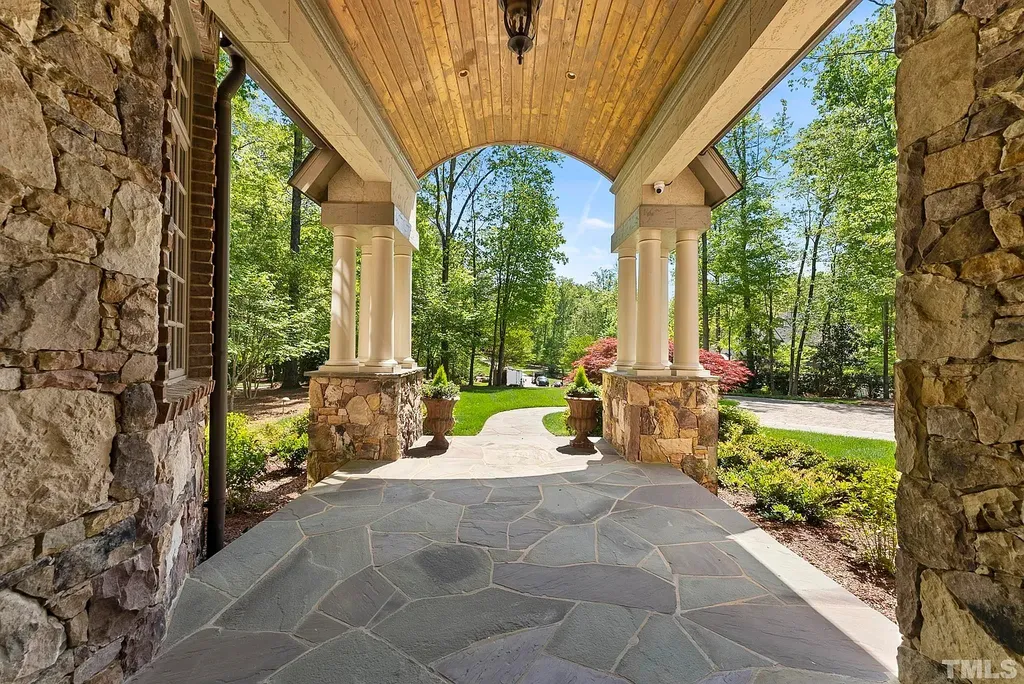 6040 Over Hadden Court Home in Raleigh, North Carolina. Indulge in the epitome of serenity and luxury at the prestigious Don Collins Estate. Nestled on 1.69 acres and embraced by the tranquil beauty of the Falls Lake wooded buffer, this remarkable residence offers an exquisite escape. Immerse yourself in timeless elegance, from the grand entrance with its stunning barreled ceiling to the imported stone accents, cathedral, coffered, and vaulted ceilings, travertine tile, and Brazilian cherry hardwood floors throughout the main level.