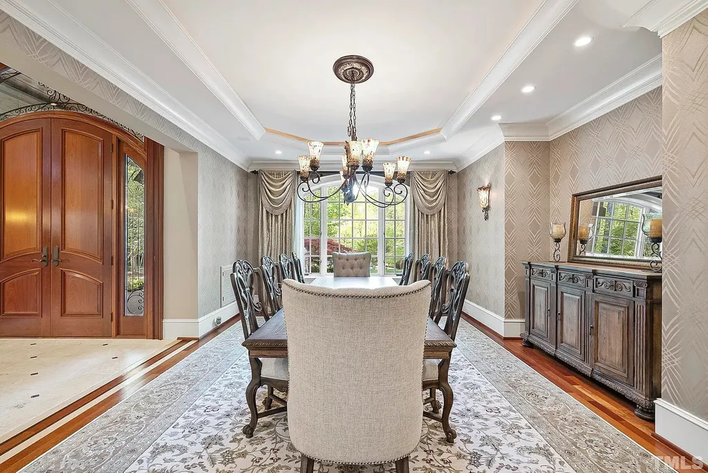 6040 Over Hadden Court Home in Raleigh, North Carolina. Indulge in the epitome of serenity and luxury at the prestigious Don Collins Estate. Nestled on 1.69 acres and embraced by the tranquil beauty of the Falls Lake wooded buffer, this remarkable residence offers an exquisite escape. Immerse yourself in timeless elegance, from the grand entrance with its stunning barreled ceiling to the imported stone accents, cathedral, coffered, and vaulted ceilings, travertine tile, and Brazilian cherry hardwood floors throughout the main level.