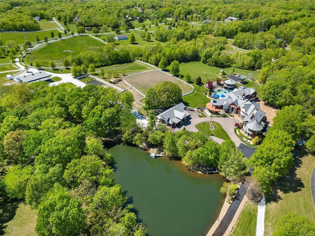 7 Hillside Court Home in Wentzville, Missouri. Prepare for a life-changing experience in this remarkable home that transcends conventional expectations. Embrace the embrace over 20,000 sq. ft. of "Luxury Meant to be Lived In," meticulously designed to cater to multigenerational families, offering abundant space for all. Situated on a vast 20+ acre property (expandable up to 130 acres), this estate presents a plethora of amenities including stables, a sports field, playground, Ferris wheel, event/sports venue, raised bed gardens, and a resort-worthy pool featuring racing slides, a swim-up bar, lazy river, waterfall-covered grotto, dive board, and a zero-edge entry.