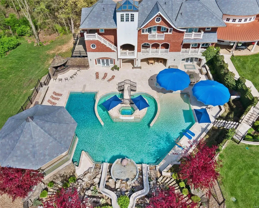 7 Hillside Court Home in Wentzville, Missouri. Prepare for a life-changing experience in this remarkable home that transcends conventional expectations. Embrace the embrace over 20,000 sq. ft. of "Luxury Meant to be Lived In," meticulously designed to cater to multigenerational families, offering abundant space for all. Situated on a vast 20+ acre property (expandable up to 130 acres), this estate presents a plethora of amenities including stables, a sports field, playground, Ferris wheel, event/sports venue, raised bed gardens, and a resort-worthy pool featuring racing slides, a swim-up bar, lazy river, waterfall-covered grotto, dive board, and a zero-edge entry.