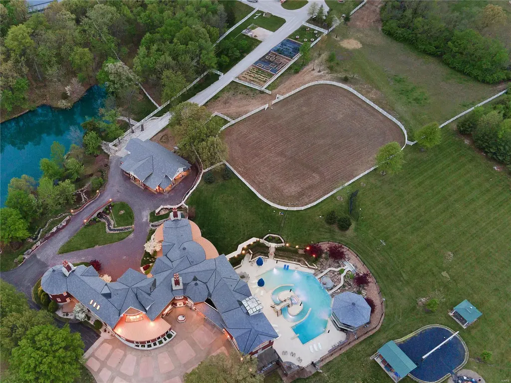 7 Hillside Court Home in Wentzville, Missouri. Prepare for a life-changing experience in this remarkable home that transcends conventional expectations. Embrace the embrace over 20,000 sq. ft. of "Luxury Meant to be Lived In," meticulously designed to cater to multigenerational families, offering abundant space for all. Situated on a vast 20+ acre property (expandable up to 130 acres), this estate presents a plethora of amenities including stables, a sports field, playground, Ferris wheel, event/sports venue, raised bed gardens, and a resort-worthy pool featuring racing slides, a swim-up bar, lazy river, waterfall-covered grotto, dive board, and a zero-edge entry.