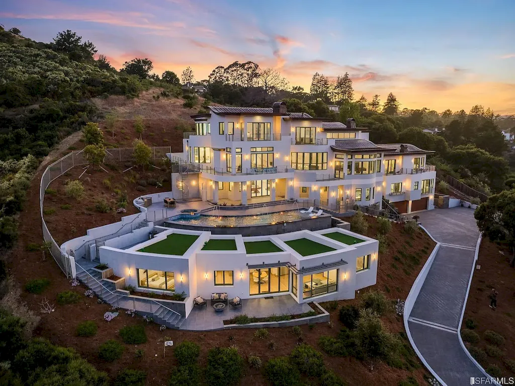 165 Woodridge Road Home in Hillsborough, California. Situated on 2.19 acres, this brand new state-of-the-art construction in Northern California boasts unobstructed, panoramic views as far as the eye can see. The architectural marvel features 26-ft high curved ceilings, rounded walls, and floor-to-ceiling windows, bathing the interior in natural light and showcasing breathtaking 180-degree bay and canyon vistas. Step onto the stunning limestone terrace, where a curved pool with a dancing water feature, spa, built-in Kalamazoo bbq station, outdoor shower, and access to a luxurious 2-bedroom, 2-bath guest house await. 