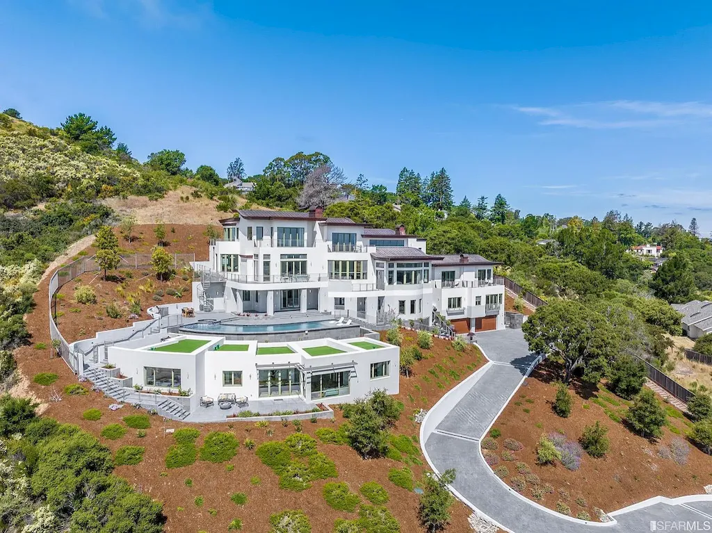 165 Woodridge Road Home in Hillsborough, California. Situated on 2.19 acres, this brand new state-of-the-art construction in Northern California boasts unobstructed, panoramic views as far as the eye can see. The architectural marvel features 26-ft high curved ceilings, rounded walls, and floor-to-ceiling windows, bathing the interior in natural light and showcasing breathtaking 180-degree bay and canyon vistas. Step onto the stunning limestone terrace, where a curved pool with a dancing water feature, spa, built-in Kalamazoo bbq station, outdoor shower, and access to a luxurious 2-bedroom, 2-bath guest house await. 