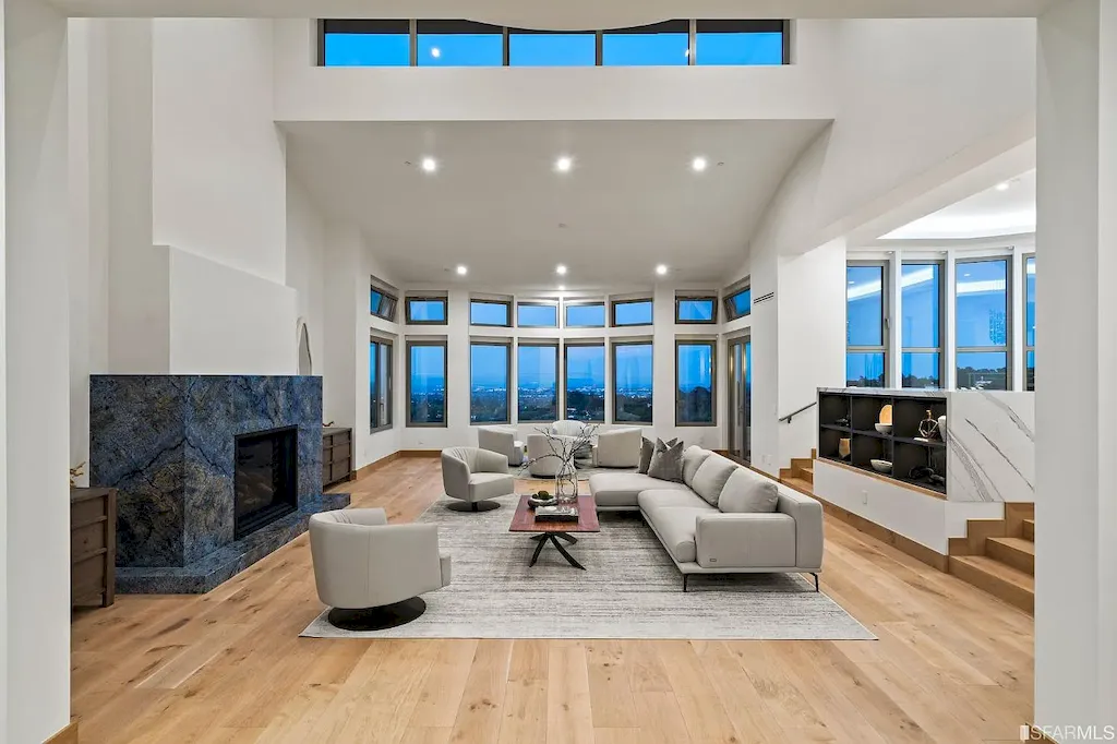 165 Woodridge Road Home in Hillsborough, California. Situated on 2.19 acres, this brand new state-of-the-art construction in Northern California boasts unobstructed, panoramic views as far as the eye can see. The architectural marvel features 26-ft high curved ceilings, rounded walls, and floor-to-ceiling windows, bathing the interior in natural light and showcasing breathtaking 180-degree bay and canyon vistas. Step onto the stunning limestone terrace, where a curved pool with a dancing water feature, spa, built-in Kalamazoo bbq station, outdoor shower, and access to a luxurious 2-bedroom, 2-bath guest house await. 