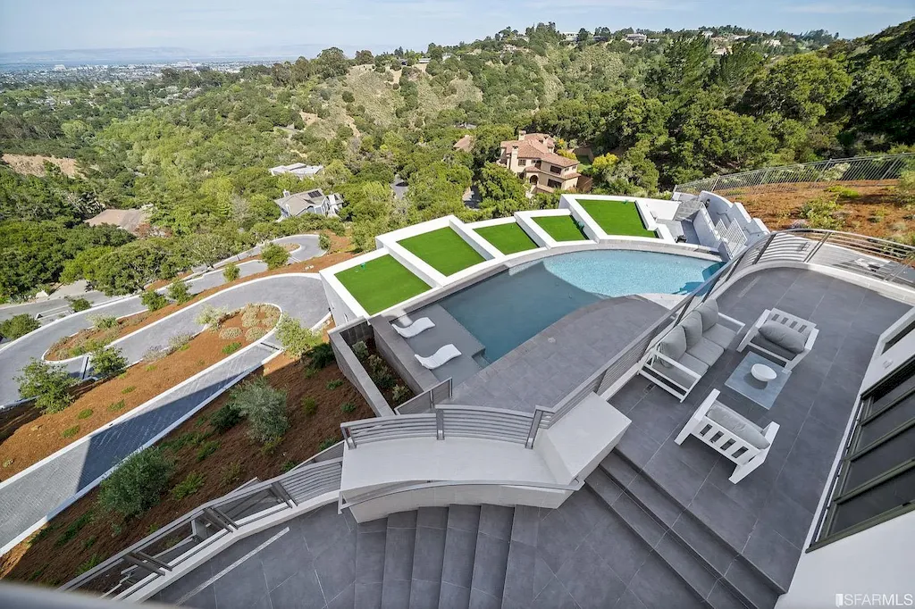 165 Woodridge Road Home in Hillsborough, California. Situated on 2.19 acres, this brand new state-of-the-art construction in Northern California boasts unobstructed, panoramic views as far as the eye can see. The architectural marvel features 26-ft high curved ceilings, rounded walls, and floor-to-ceiling windows, bathing the interior in natural light and showcasing breathtaking 180-degree bay and canyon vistas. Step onto the stunning limestone terrace, where a curved pool with a dancing water feature, spa, built-in Kalamazoo bbq station, outdoor shower, and access to a luxurious 2-bedroom, 2-bath guest house await. 