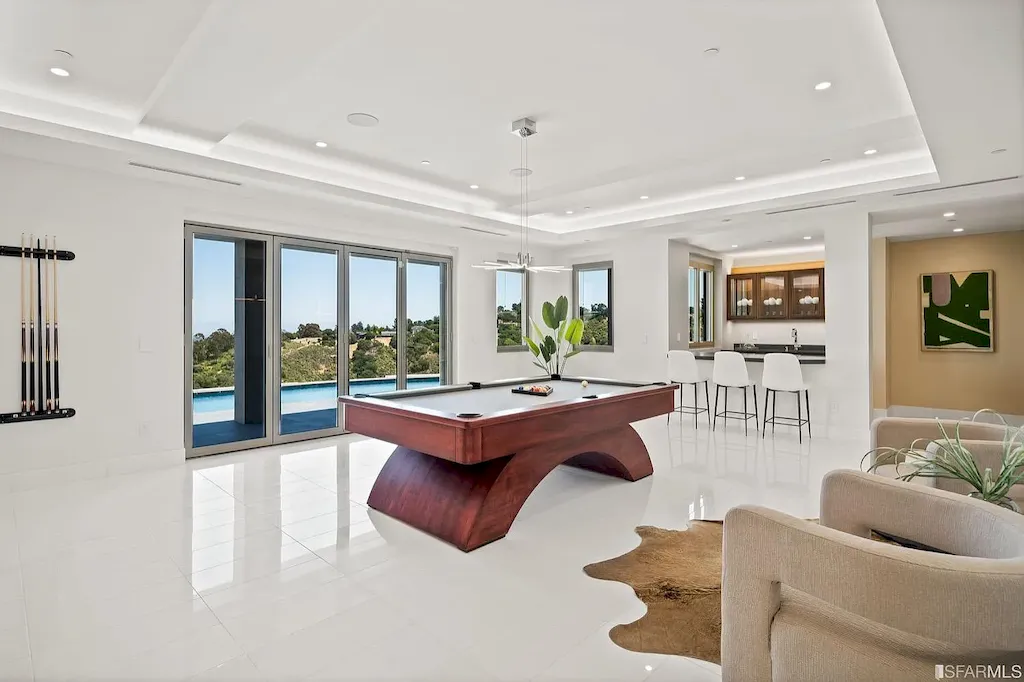 165 Woodridge Road Home in Hillsborough, California. Situated on 2.19 acres, this brand new state-of-the-art construction in Northern California boasts unobstructed, panoramic views as far as the eye can see. The architectural marvel features 26-ft high curved ceilings, rounded walls, and floor-to-ceiling windows, bathing the interior in natural light and showcasing breathtaking 180-degree bay and canyon vistas. Step onto the stunning limestone terrace, where a curved pool with a dancing water feature, spa, built-in Kalamazoo bbq station, outdoor shower, and access to a luxurious 2-bedroom, 2-bath guest house await. 